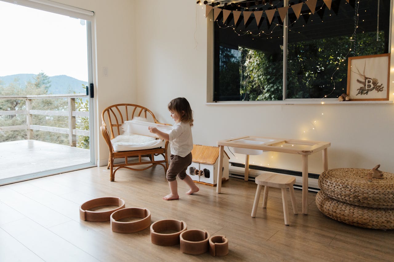 Child playing in a cozy, light-filled playroom with wooden toys and decor.